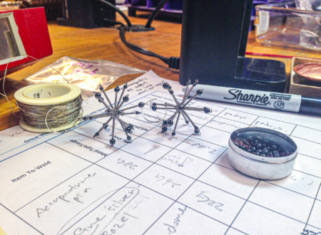 Metal arts studies sit on a sheet of paper with notes on it