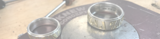 Two silver rings on a work bench